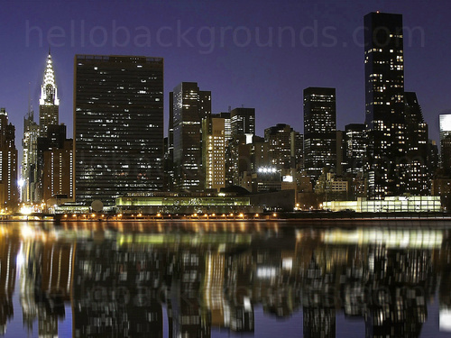 Urban cityscape at night featuring various tall buildings with some displaying lights from windows next to waterside Skype background