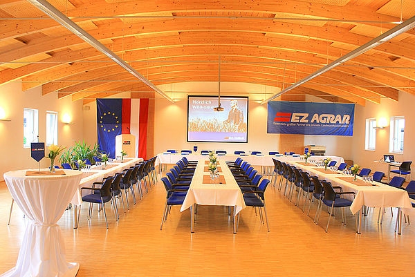 Image of banquet hall with a beamer at the front and a big EZ Agrar Logo