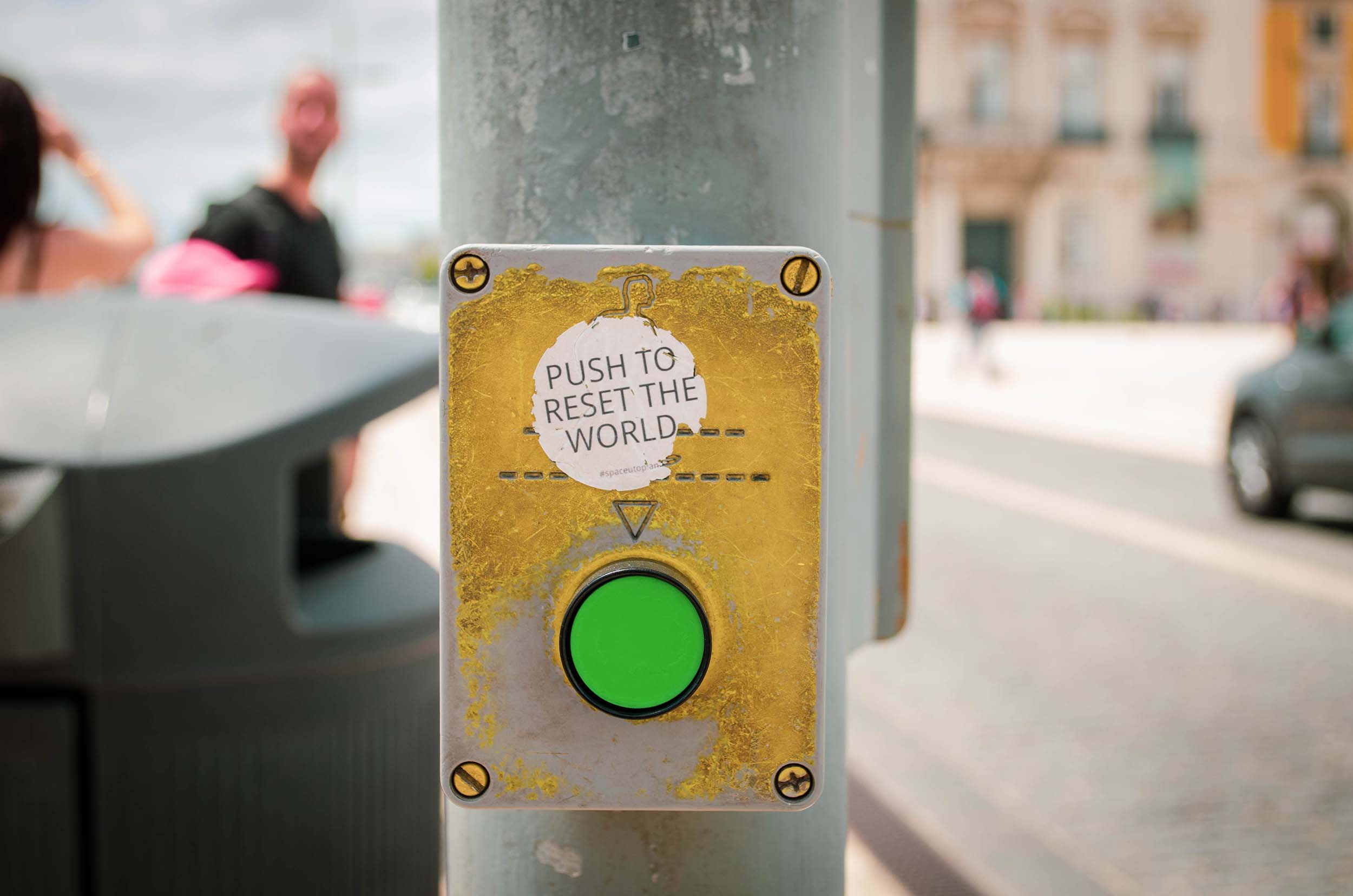 A crosswalk button with push to reset the world sticker on it