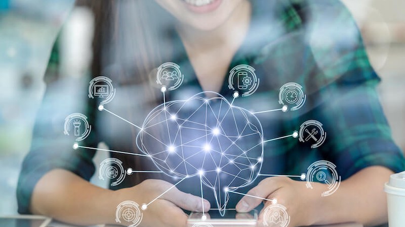 Woman holding smartphone overlaid with holographic brain shape and symbols for technological concepts