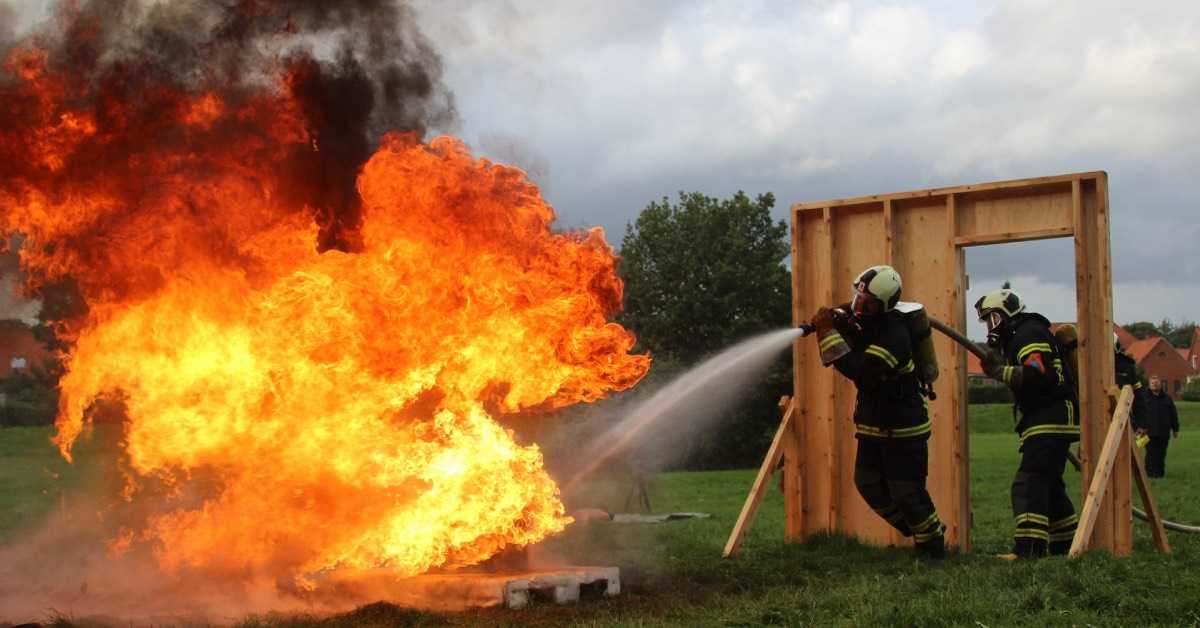 Zwei Feuerwehrleute löschen bei einer Schauübung einen großen Brand