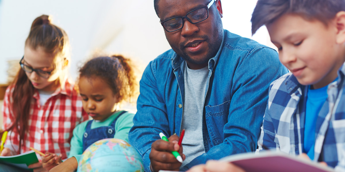 Switch from Teaching to UX Design A teacher sitting in a group of students, looking at an assignment