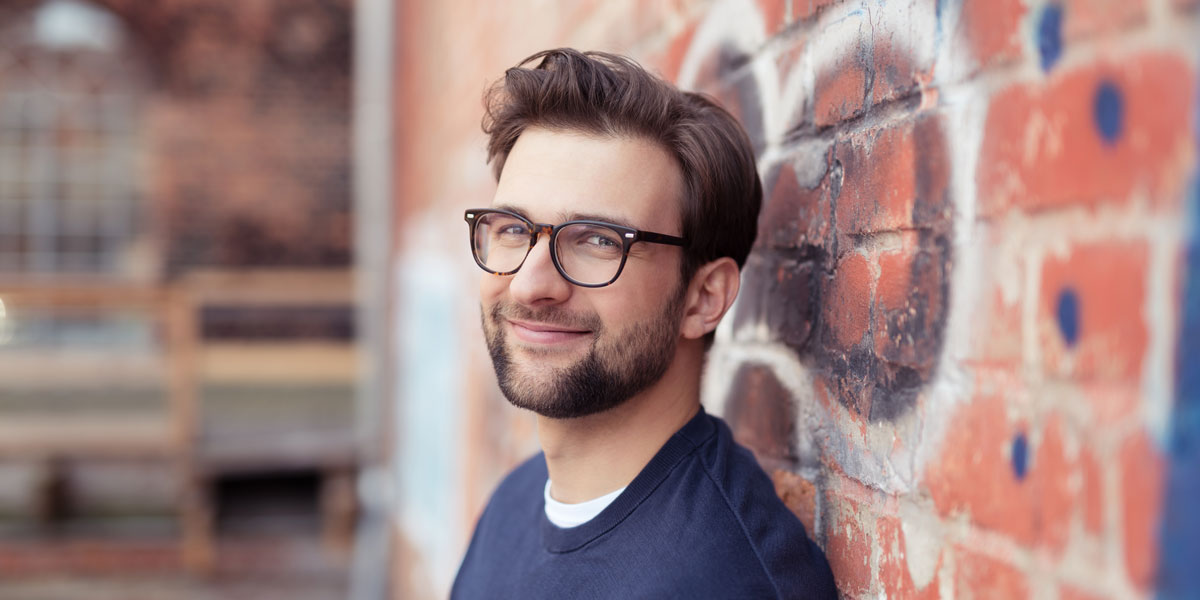 A web developer leaning against a wall A web developer leaning up against a brick wall