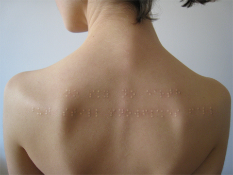 Klara Jirkova's Braille tattoo, a two-row pattern of tactile sentences across the upper back of a woman's body.