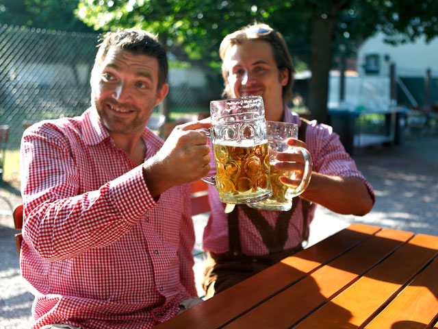 People raising beer steins to clink glasses together