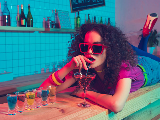 A girl enjoying a martini and several shots of hard liquor