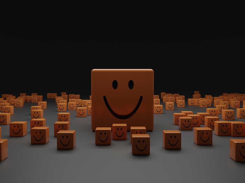 A table full of blocks with smiling faces on with one big smiling face block in the middle, Photo by Shubham Dhage on Unsplash