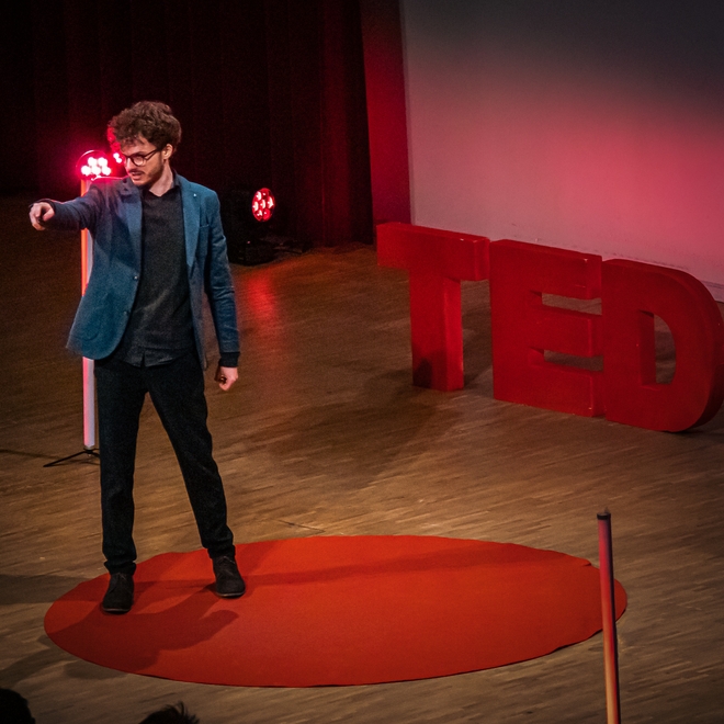 Thomas Winters presenting an improvised TEDx talk generated using TalkGenerator during his talk at TEDxLeuven.