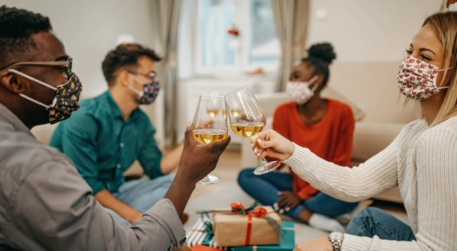 Four young people sharing glasses of wine and exchanging gifts