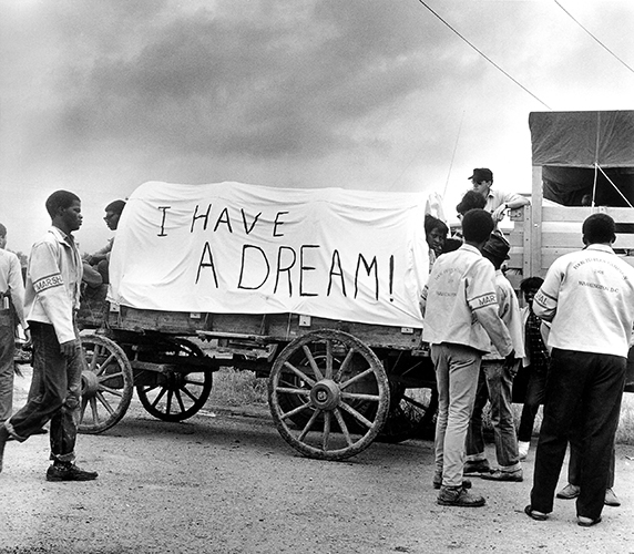 A black and white photo of a Mule Train with 'I Have A Dream' written on the wagon's canvas cover.
