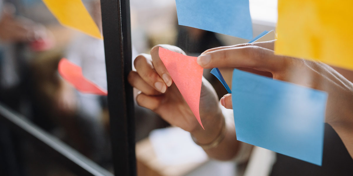 A UX designer arranging Post-It notes A UX designer arranging Post-It notes on a glass wall