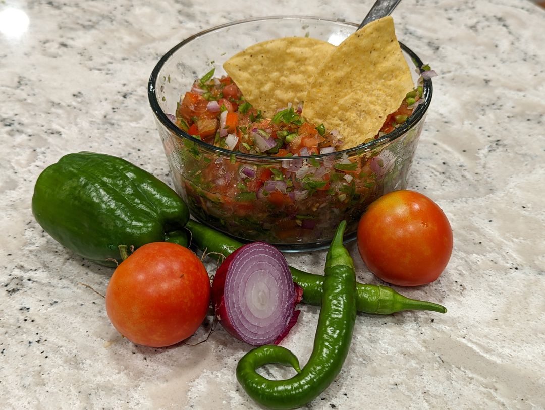Salsa veggies next to a bowl of fresh salsa.