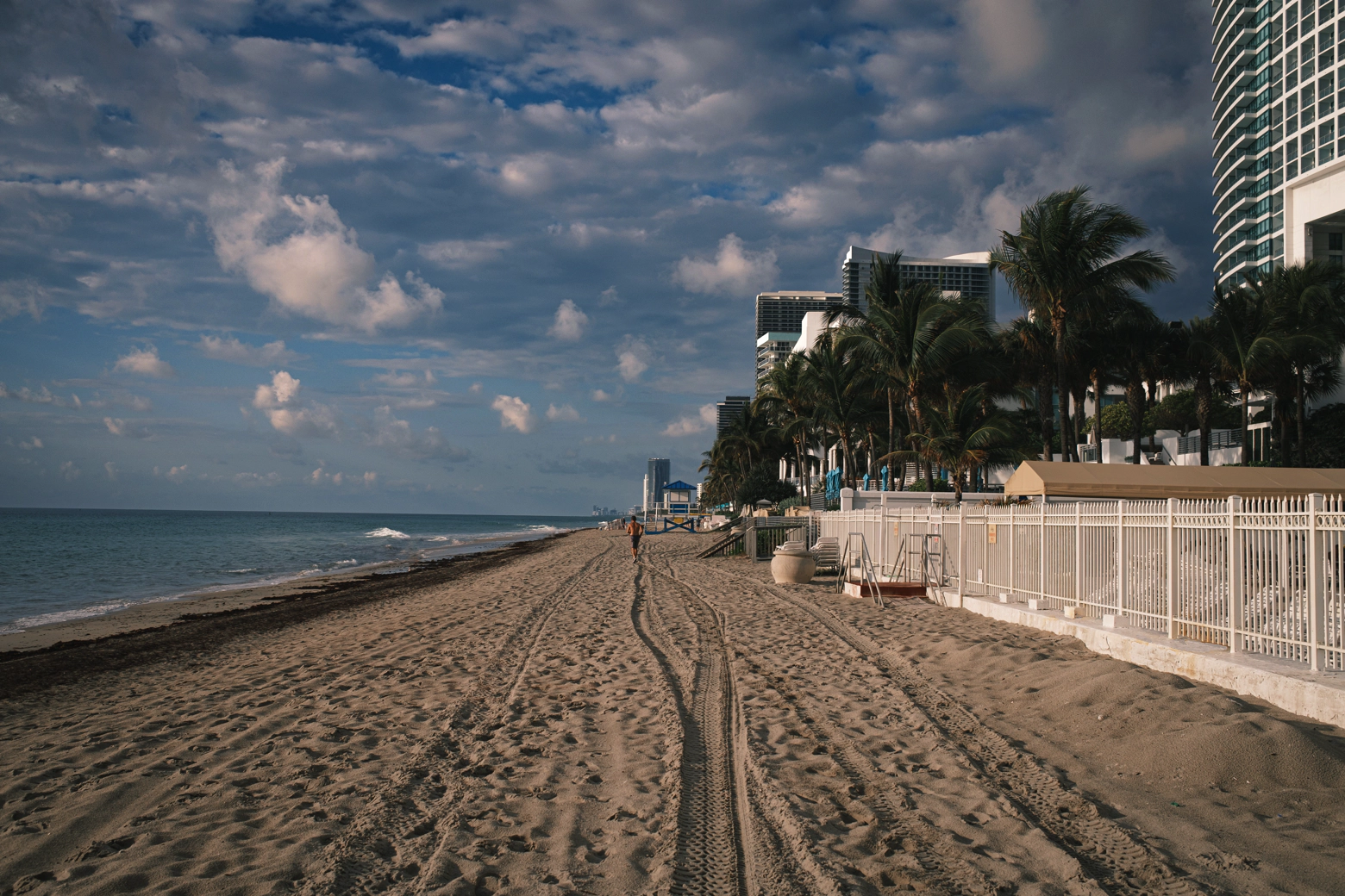 A beach in Florida. Soft clouds. Scratches and footsteps in the sand. A jogger running into the distance.