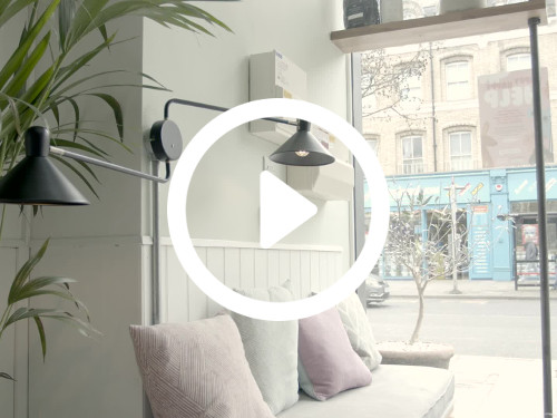 Calm pastel coloured meeting space with padded bench with cushions and urban street views through large window Microsoft Teams background