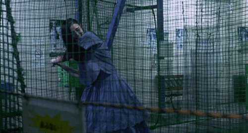 An animated gif of a scene from the movie 'Fumiko's Legs' of a drunk woman wildly swinging a bat at a batting center.