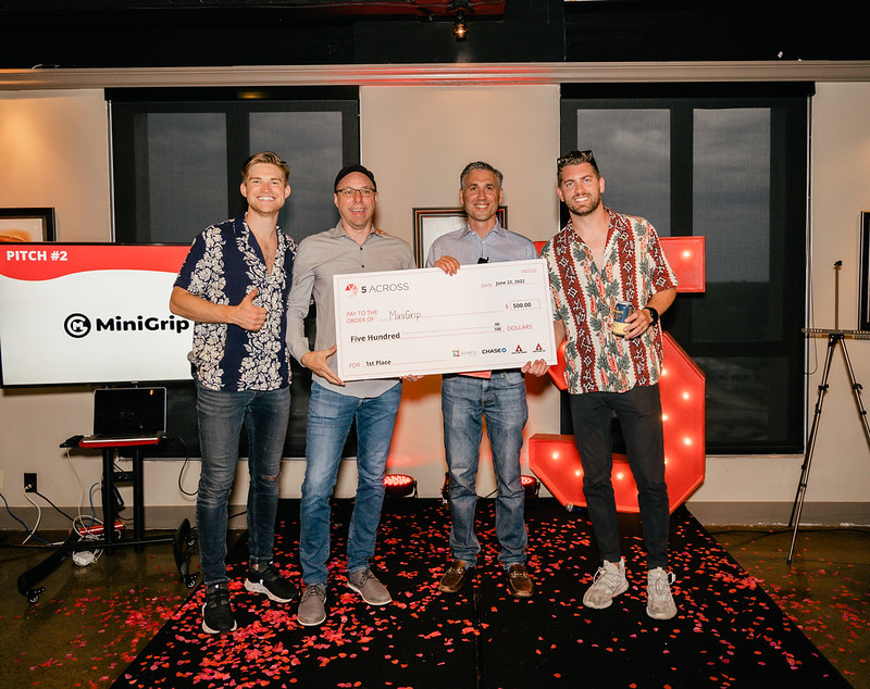 Founders of MiniGrip hold a giant check for $500 after winning the 5 Across June Pitch Competition