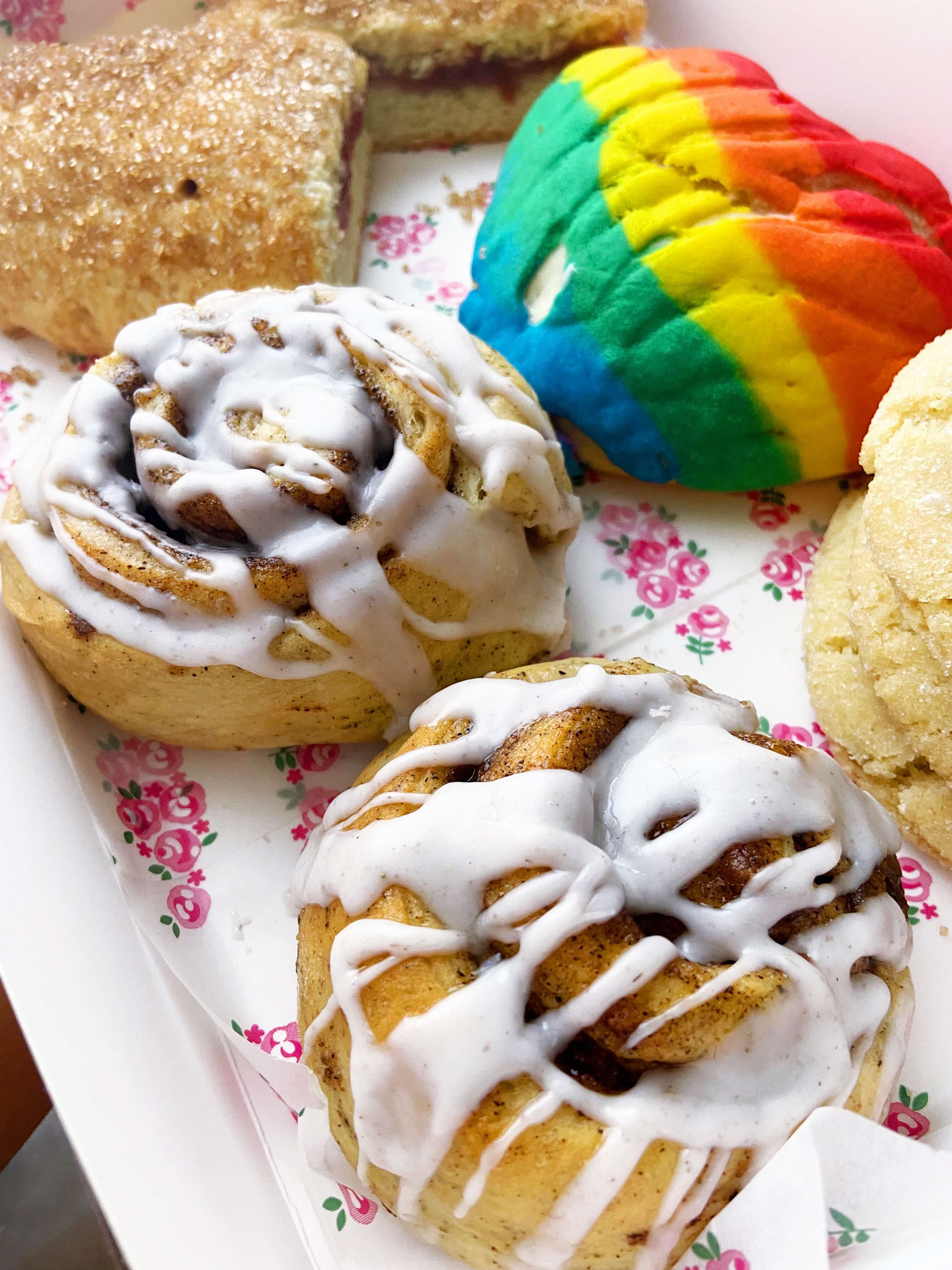 a plate of cinnamon rolls, cookies, and conchas