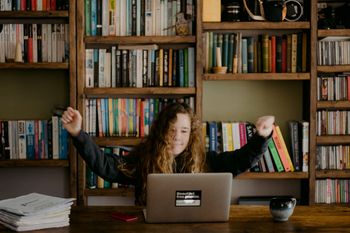 A girl celebrating learning in front of a laptop