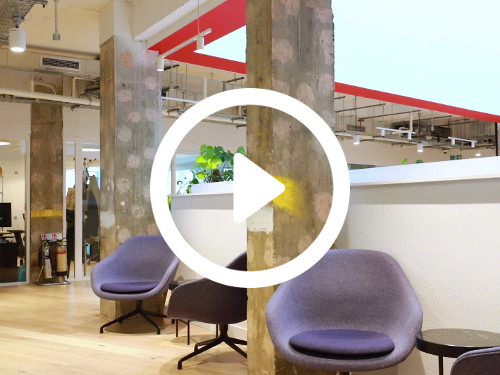 Open workspace featuring large decorated pillars next to modern design purple egg chairs by small black round tables Microsoft Teams background