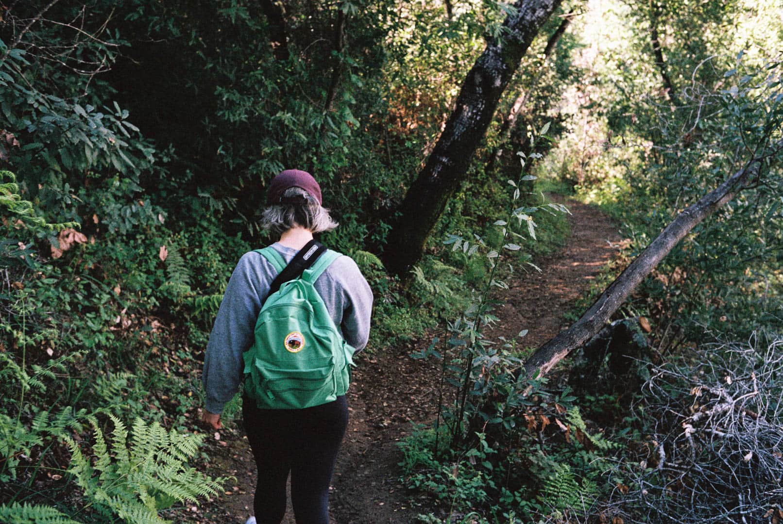 A woman wearing a green backpack on a hiking trail