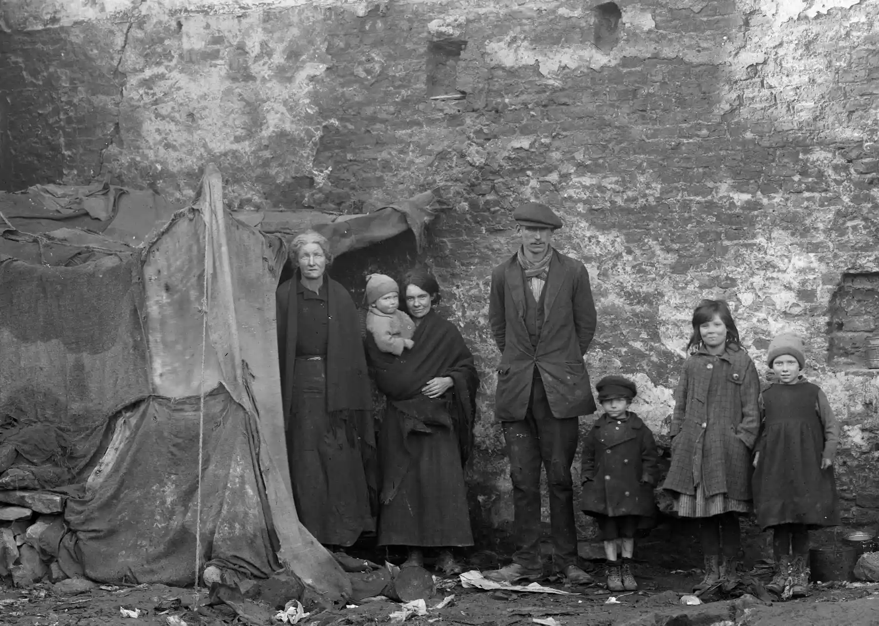 A group of Irish people from the 1800s beside a makeshift shelter