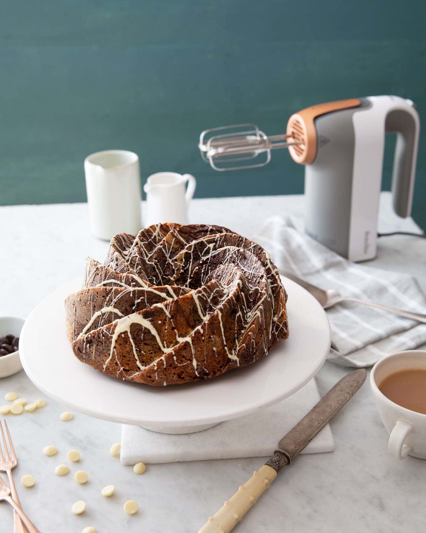 walnut swirl chocolate cake with a breville heat soft mixer in the background with a cup of tea and baking utensils.