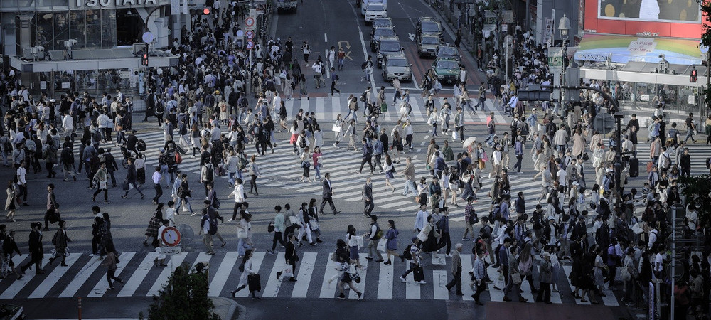 A busy intersection with people walking across in every possible direction