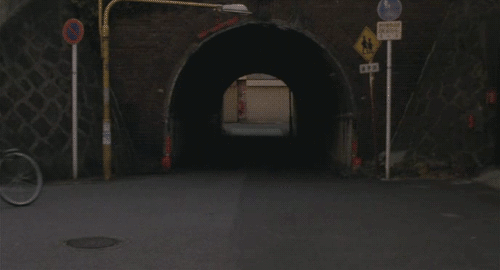 An animated gif of a scene in the movie 'Maborosi' showing a woman riding her bicycle through a commuter train underpass.