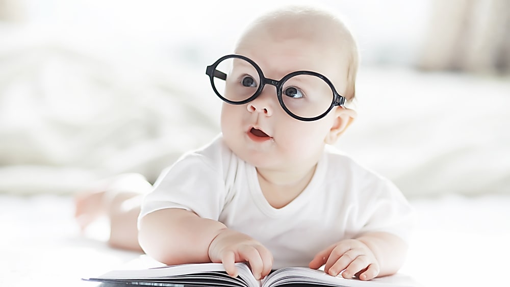 baby with glasses reading a book