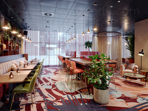 Artistic cafe interior containing high tables with stools and square wooden tables with green padded chairs Skype background