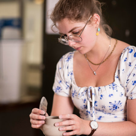 Francesca fettling the neck of a slipcast clay vessel prior to firing.