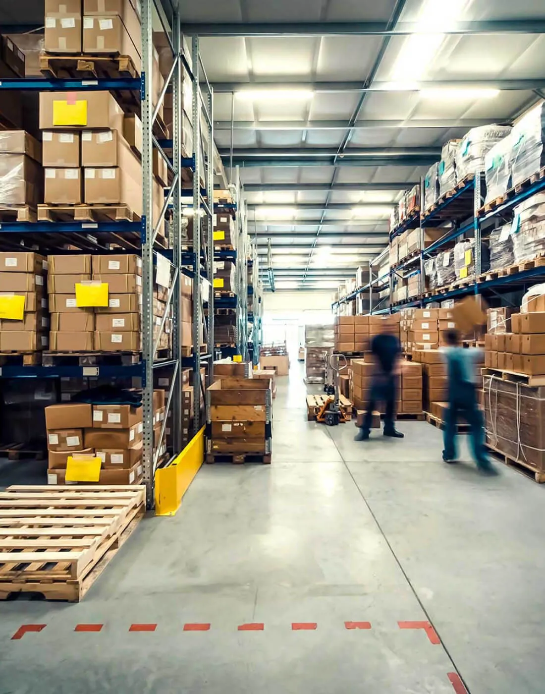 image of two workers moving boxes in a warehouse with a blurred effect to show movement