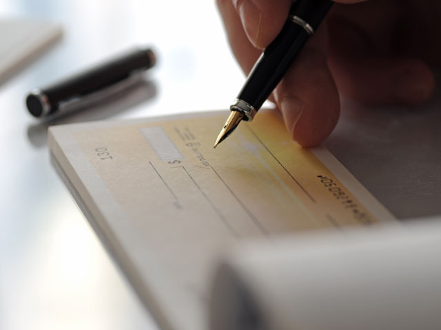 A person writing a check from their checkbook