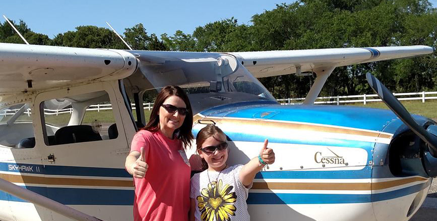 Photo of woman and daughter by a Code 1 training airplane