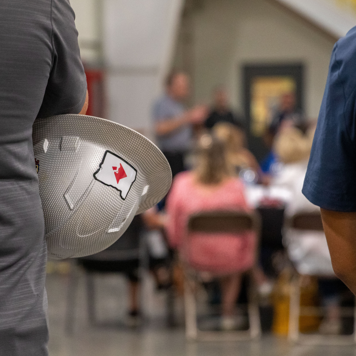 Closeup of Cardinal hardhat with VPP presentation in the background.