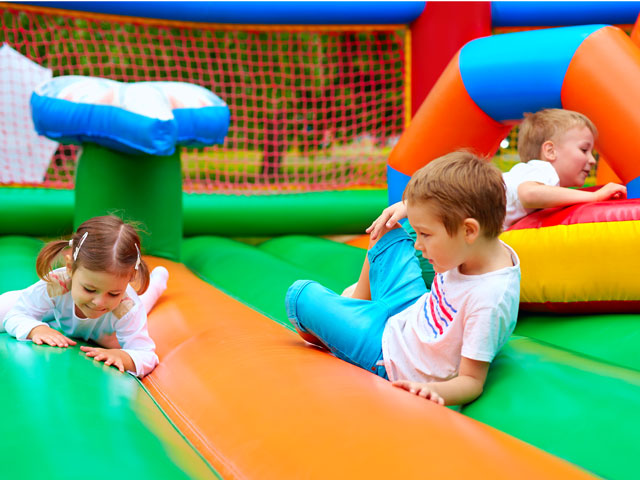 Multiple children playing on a bounce house.