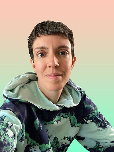 Portrait of Emily, gender-ambiguous person, with short brown hair, hazel eyes, and a warm smile. They are wearing a hoodie with an all-over-print of a synthetic-sliced-mineral-looking swirling acid pattern that is seafoam green, light cyan, and deep dark blue. Behind them is an artificial background gradient that is peach at the top and seafoam green at the bottom. mood: #acidtropical