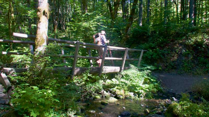 Dave crosses a bridge over a creek