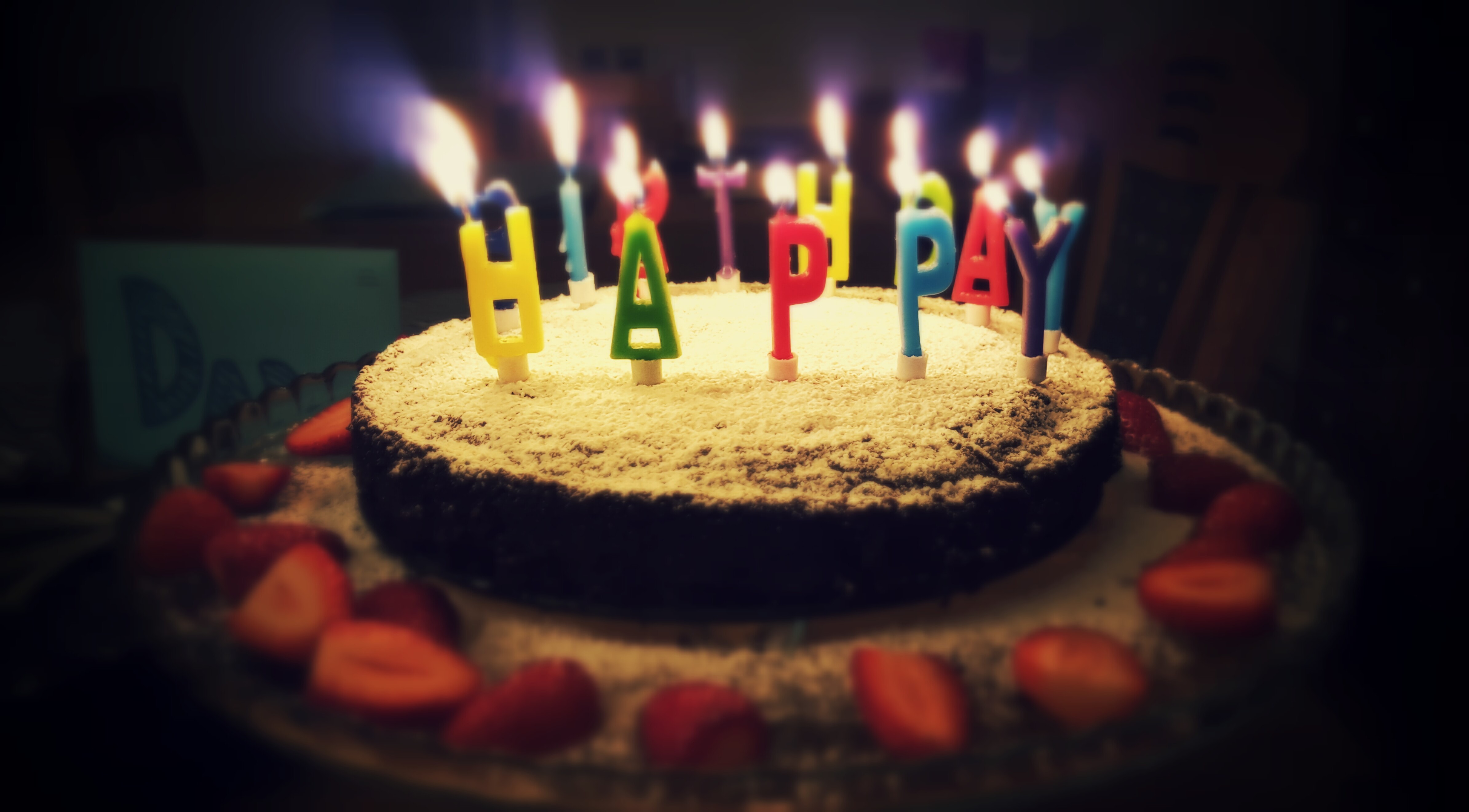 round cake with candles and "happy birthday" sign