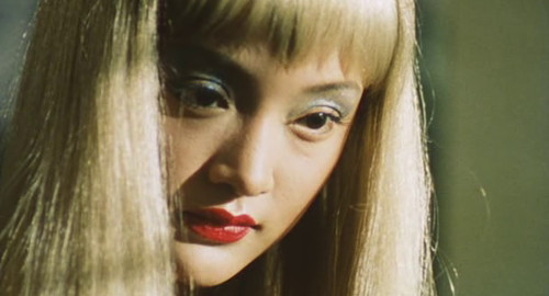 A close-up screenshot from the movie 'Suzhou River' of a young woman with blonde hair (played by Zhou Xun).