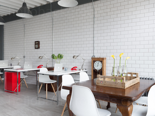 Retro style shared workspace featuring metro wall tiles next to wooden desks and white chairs by analogue clock  Zoom background