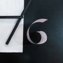 A pair of black chopsticks on a napkin makes a seven alongside a curled receipt forming a tidy six on a black surface.
