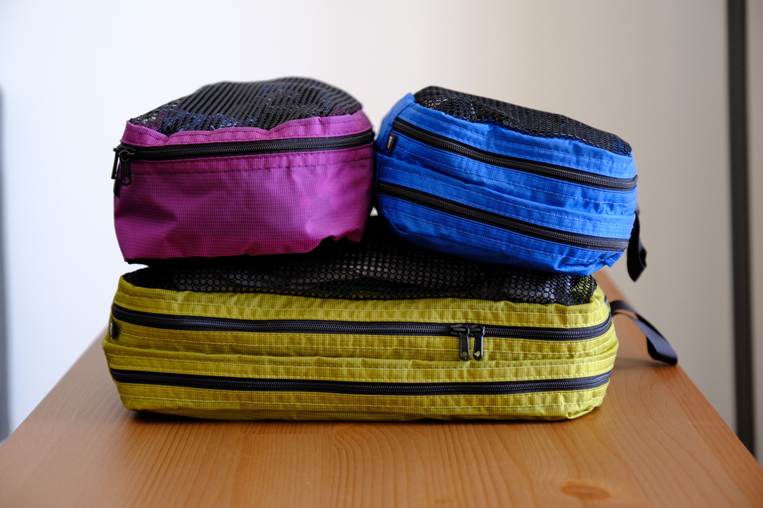 From top left to right: Small basic packing cube in Violet, Small laundry packing cube in Island (blue) and large launcy packing cube in Wasabi (yellow):