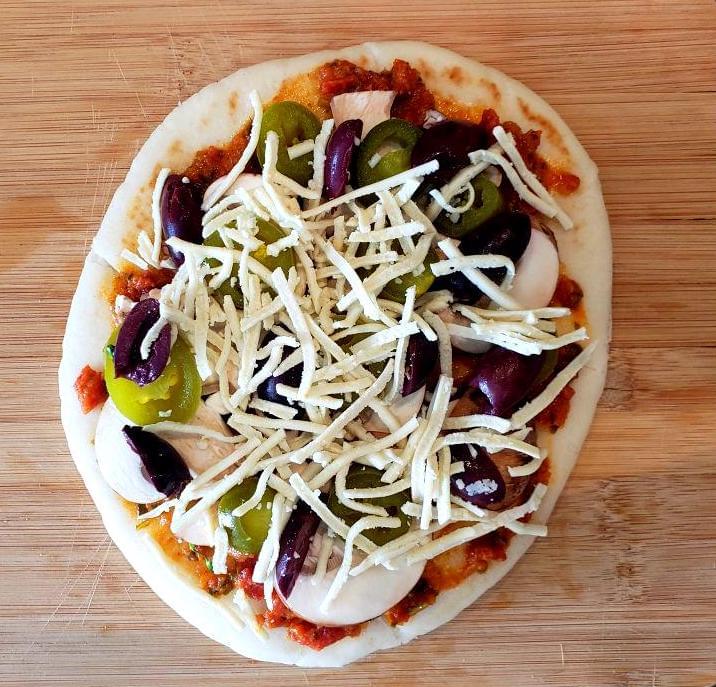 Uncooked flatbread with jalapeño, olives, and mushroom
