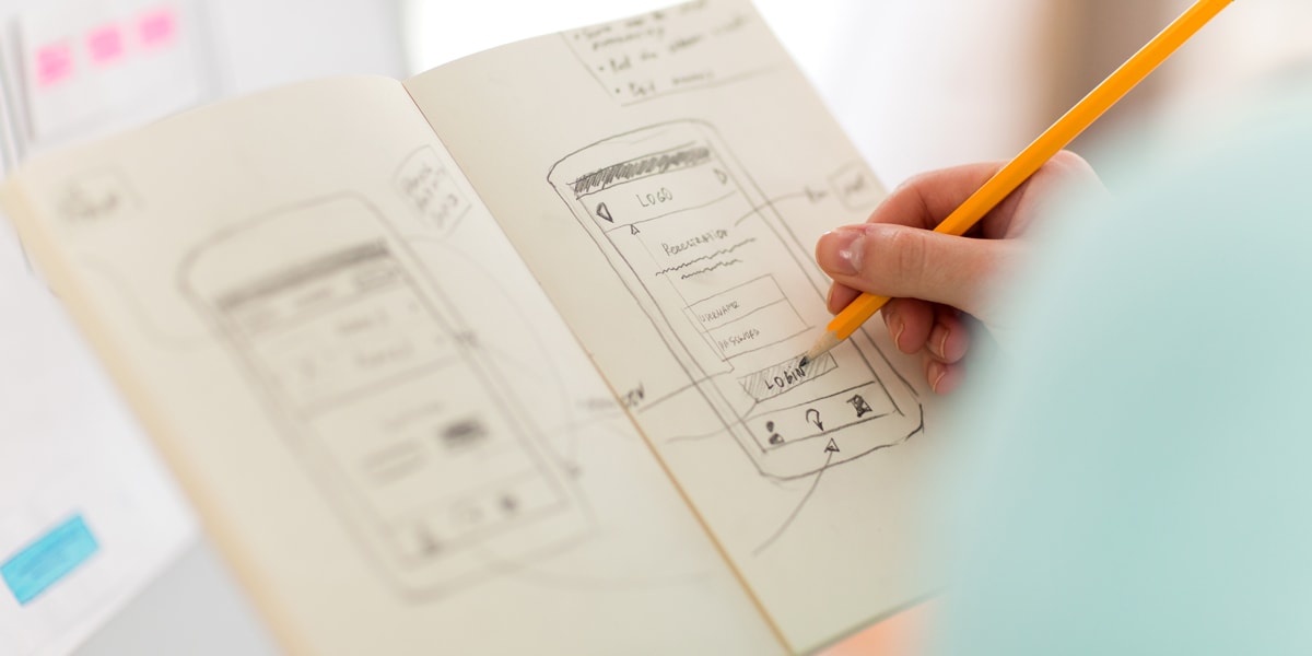 How to conduct a redesign: A UX designer sketching out a wireframe A UX designer sketching out a wireframe in a notebook