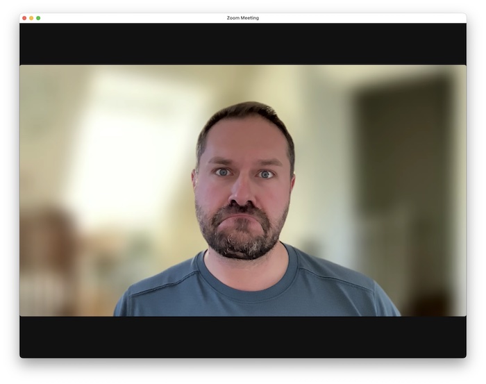 A screenshot of a face during a Zoom call taken with the low-quality Apple Studio Display built-in webcam