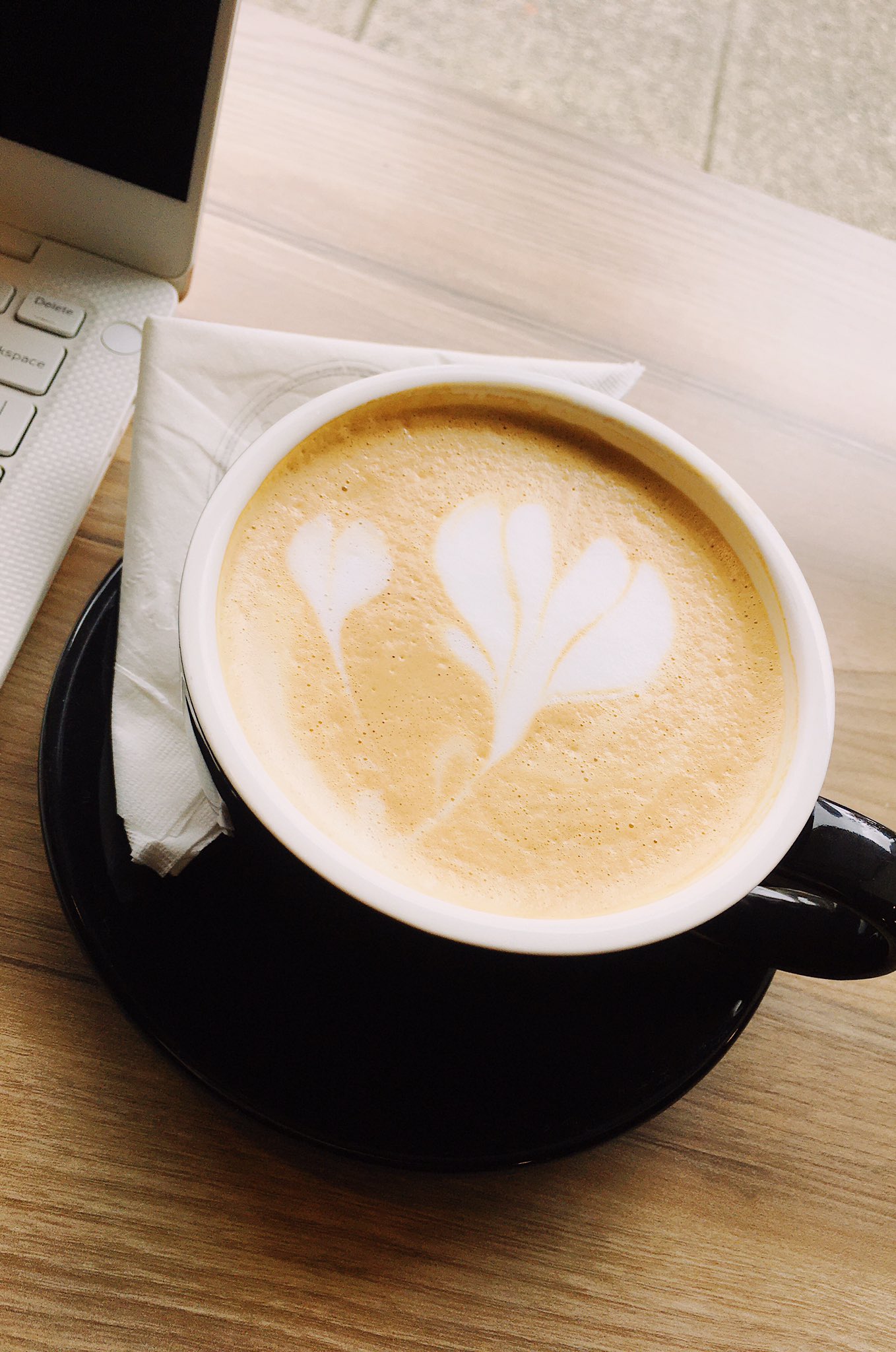 A cute latte with a heart, next to my laptop at a cafe.