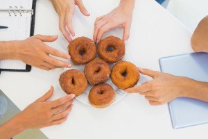 Business team reaching for doughnuts on table