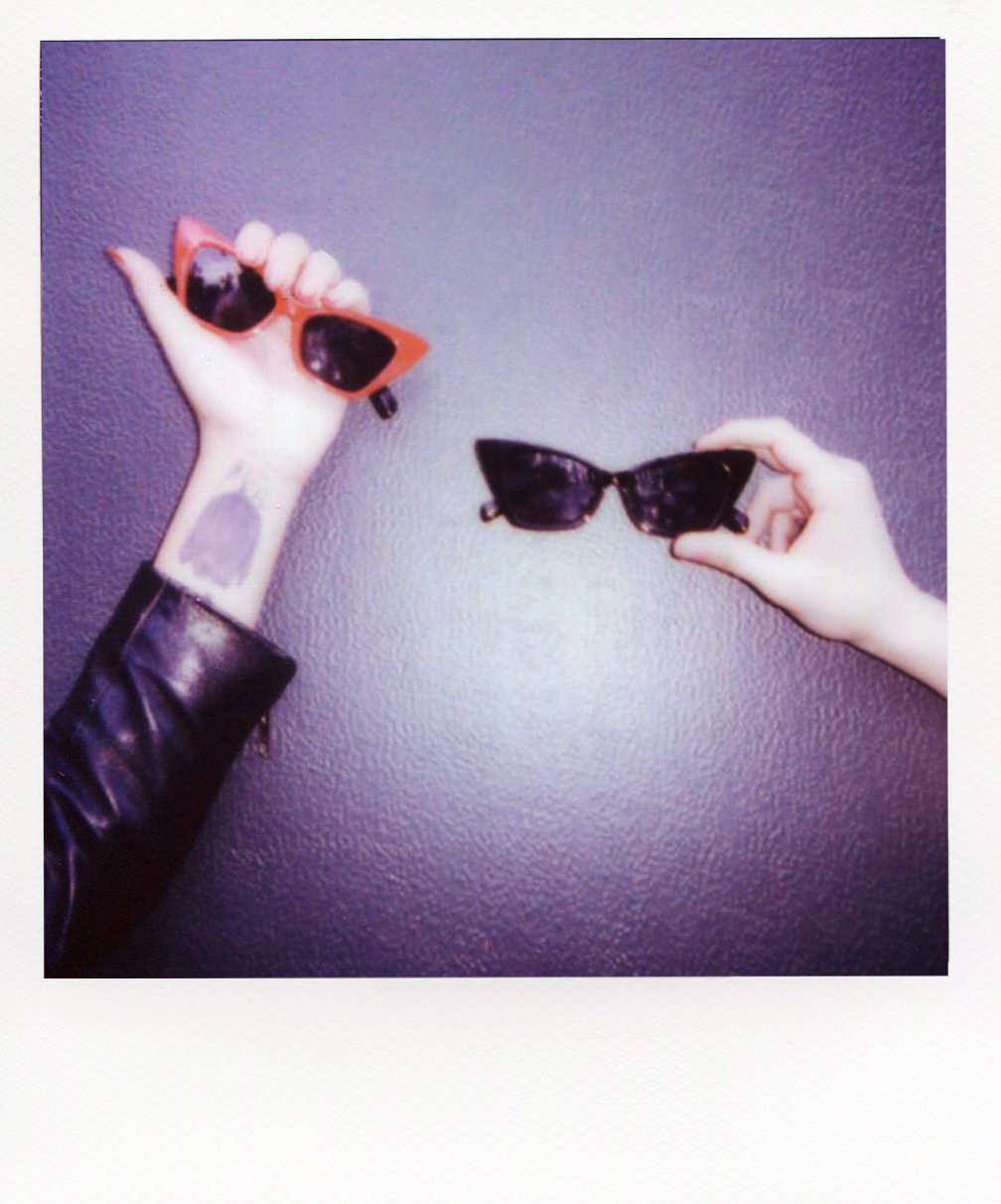 Two hands holding Evil Eye Wear sunglasses