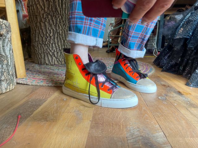 Low angle reverse wearing the shoes,
right foot outside is yellow with orange lacing panel.
Left foot inside is blue low-top with orange lining
that transitions to silver/black stripes and orange upper

